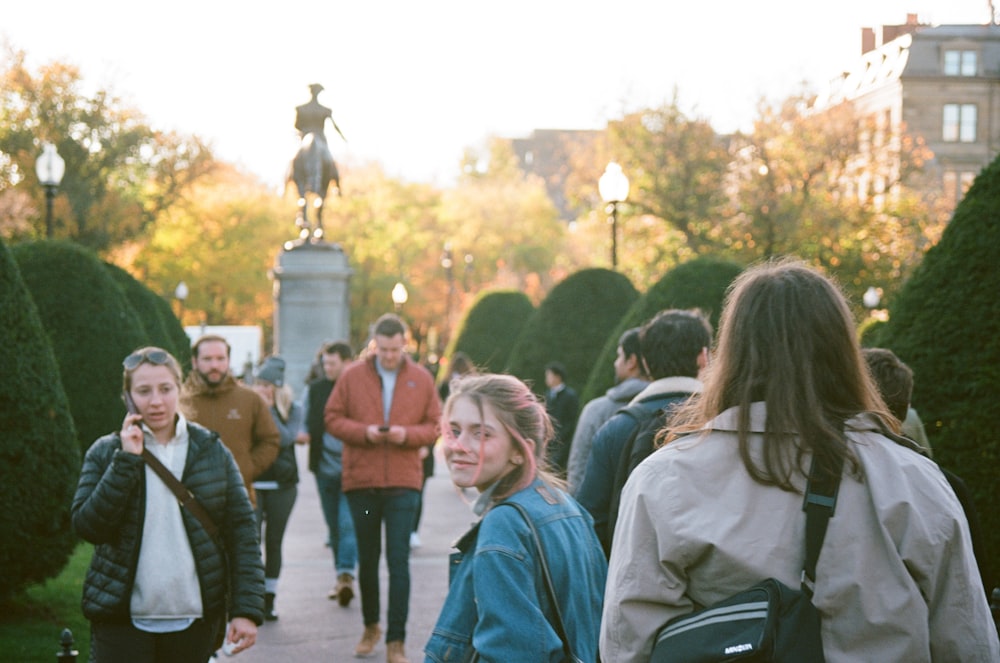 selective focus photography of crowd walking near statue during daytime