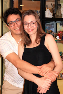 A happy couple holding their 3D printed wedding figurines, smiling at the camera.