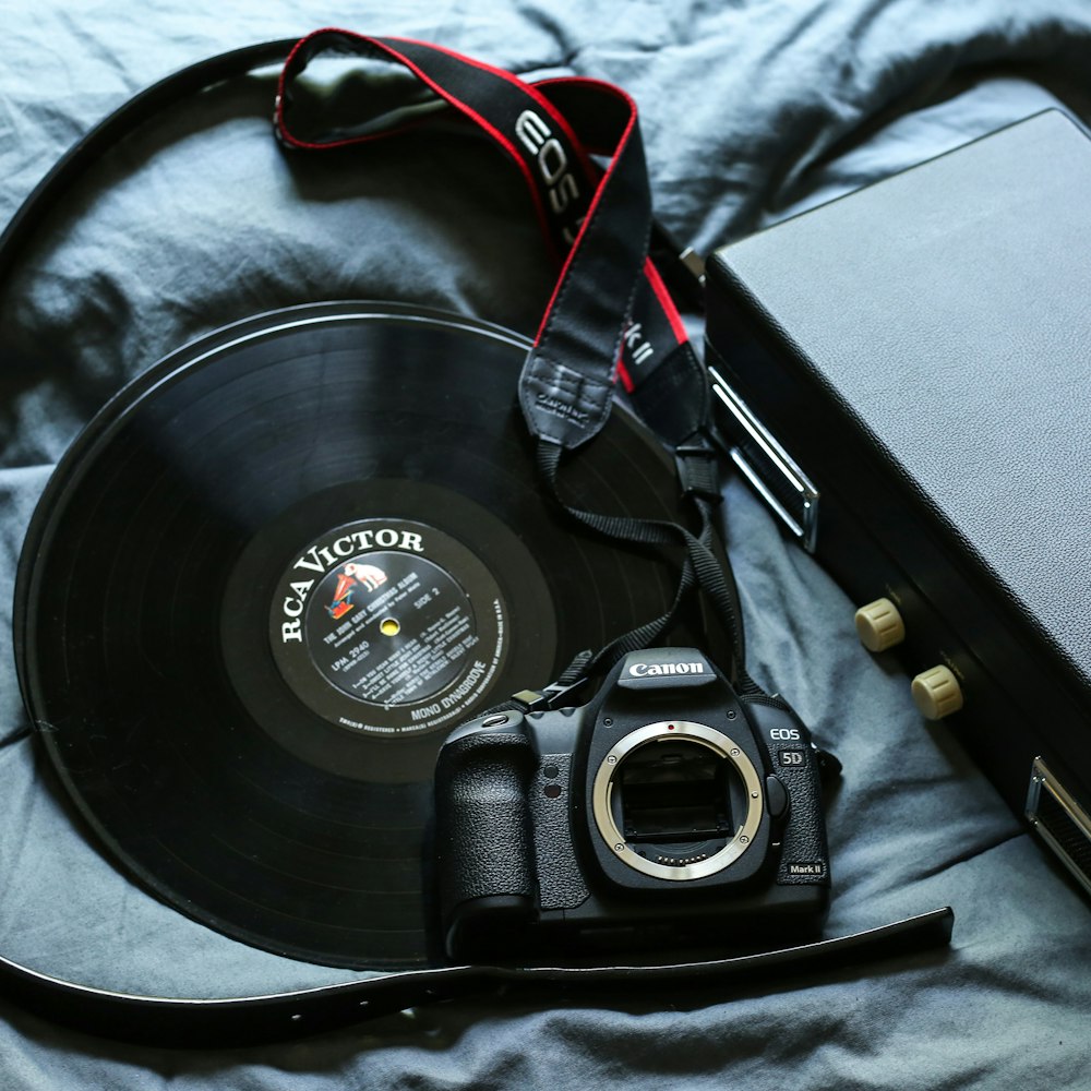 black Canon EOS 5D DSLR camera beside black RCA Victor vinyl record