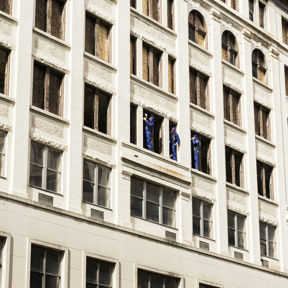 three men standing on building window panels