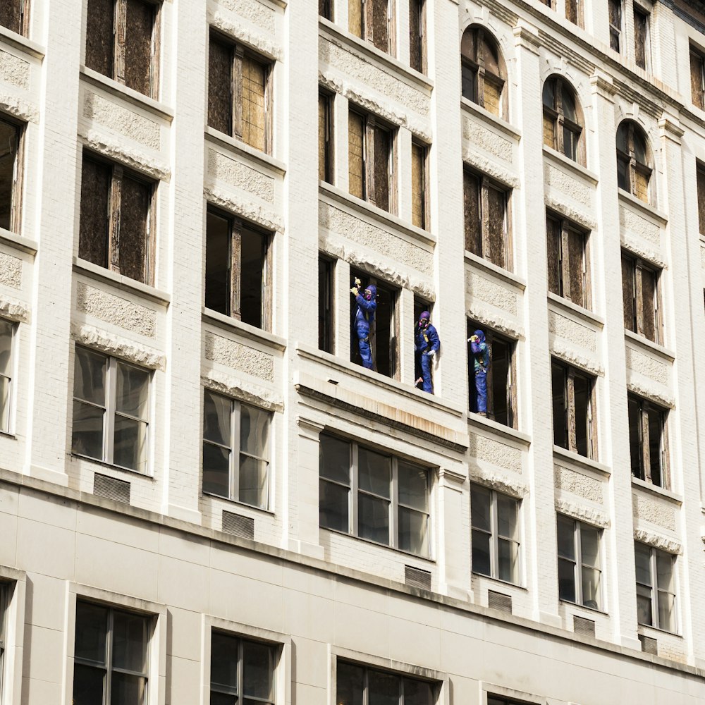 Tres hombres de pie sobre los paneles de la ventana del edificio