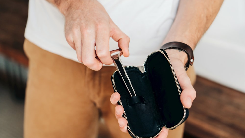 shallow focus photo of person holding black pouch bag