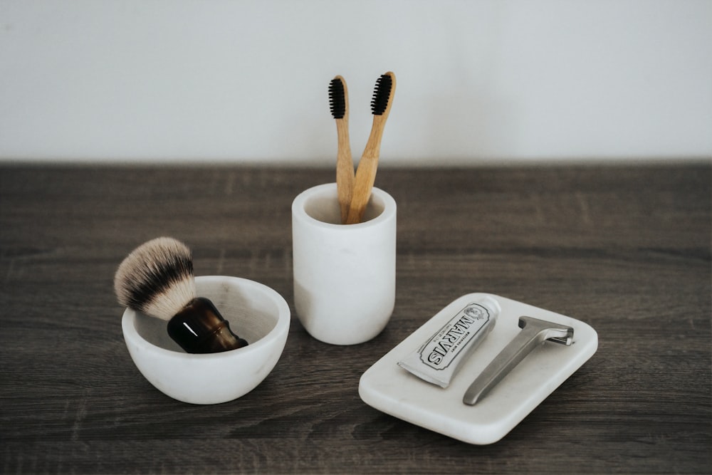 shallow focus photo of two brown brushes in white ceramic cup