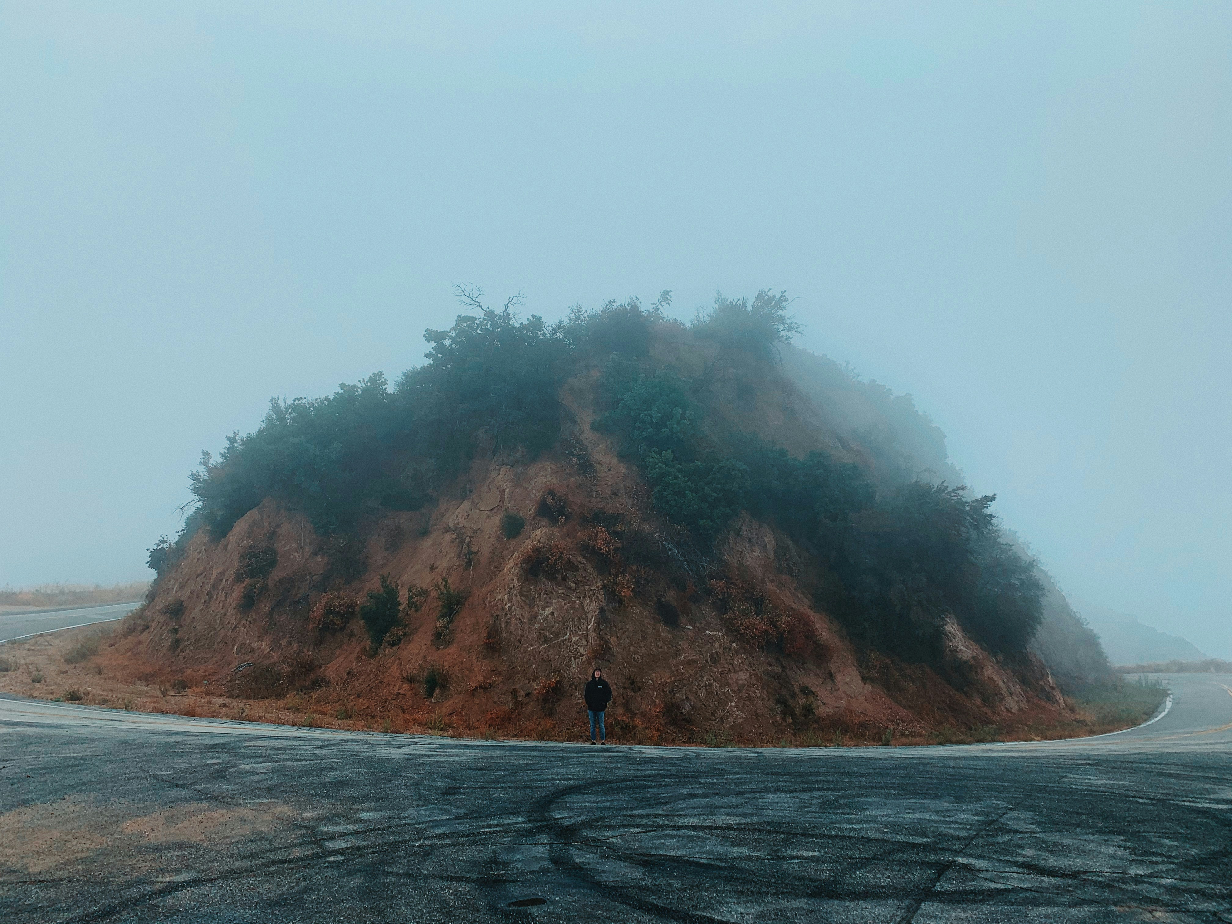 homem vestindo jaqueta preta em pé na estrada de asfalto