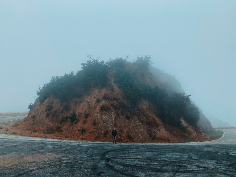 man wearing black jacket standing on asphalt road