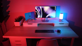 A clean, minimalist desk setup with a plant, notebook, and a glowing blue light symbolizing focus.