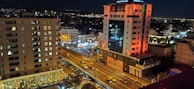 A bustling city street at night with illuminated buildings.