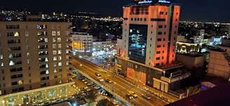 A bustling city street at night with illuminated buildings.