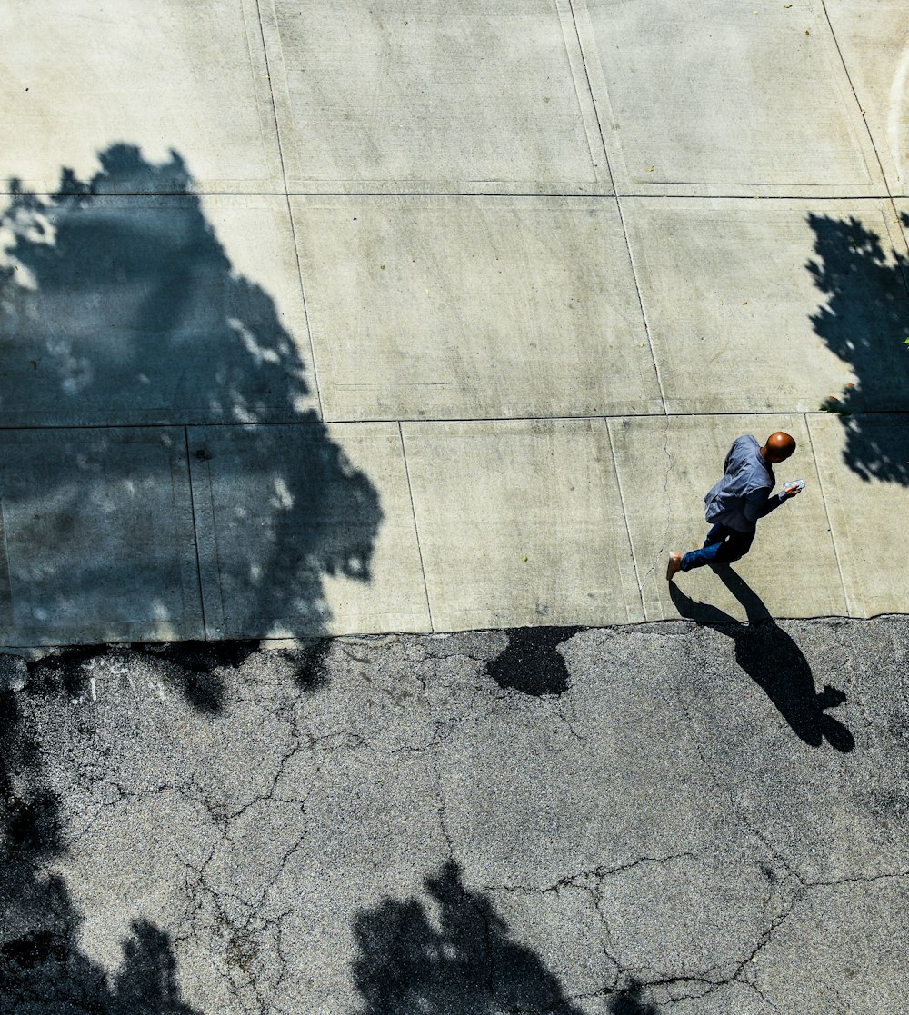 man using phone while walking on pathway during daytime