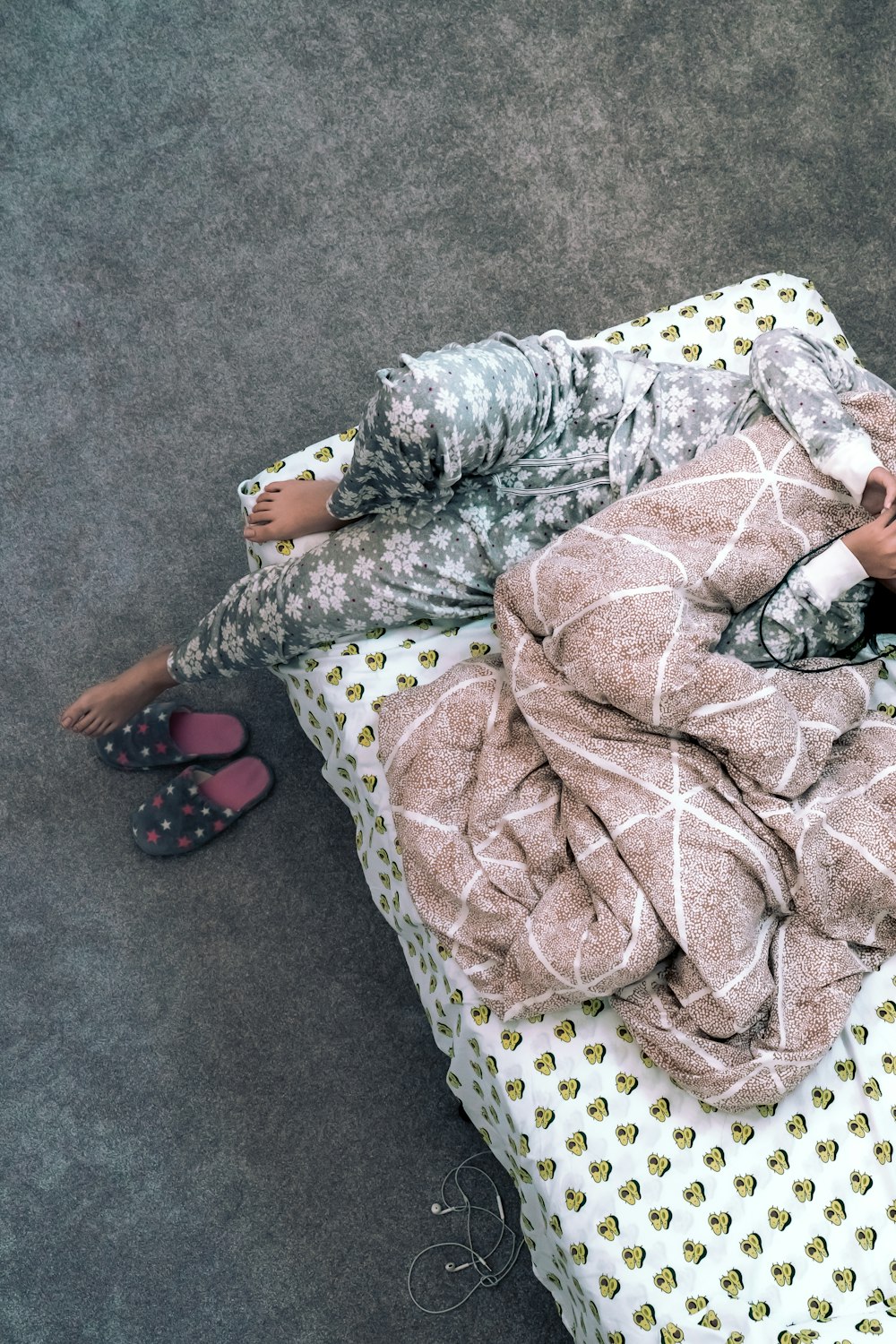 person lying in bed with gray blanket
