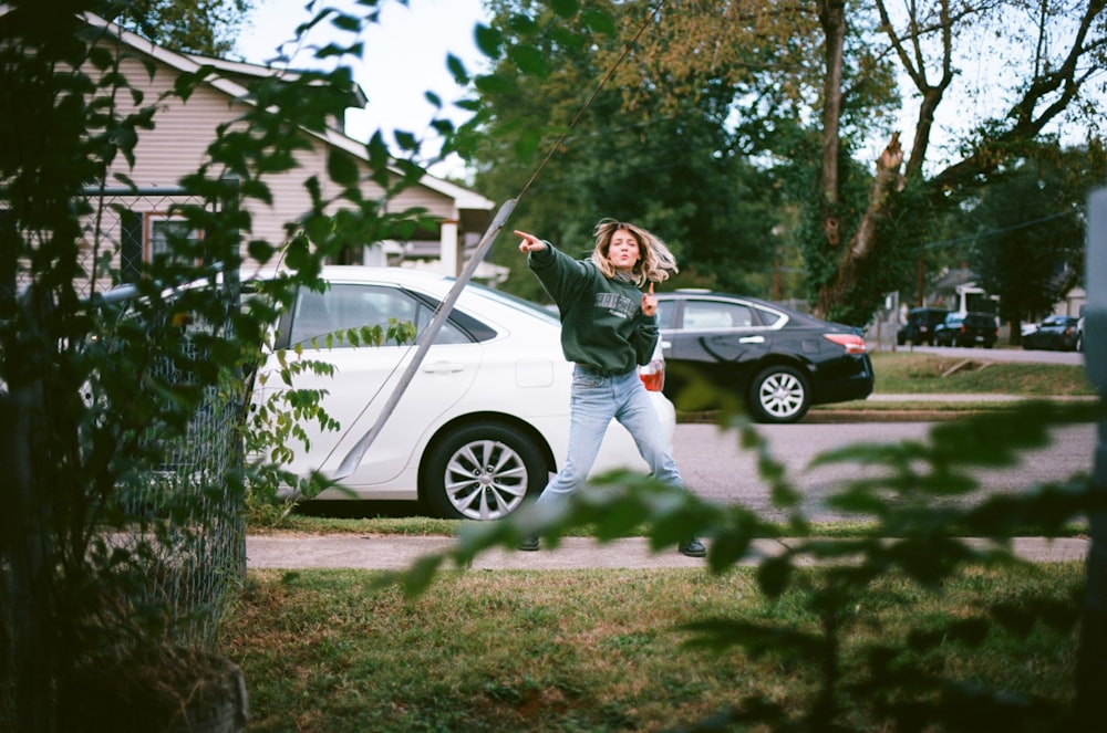 woman standing pointing beside sedan