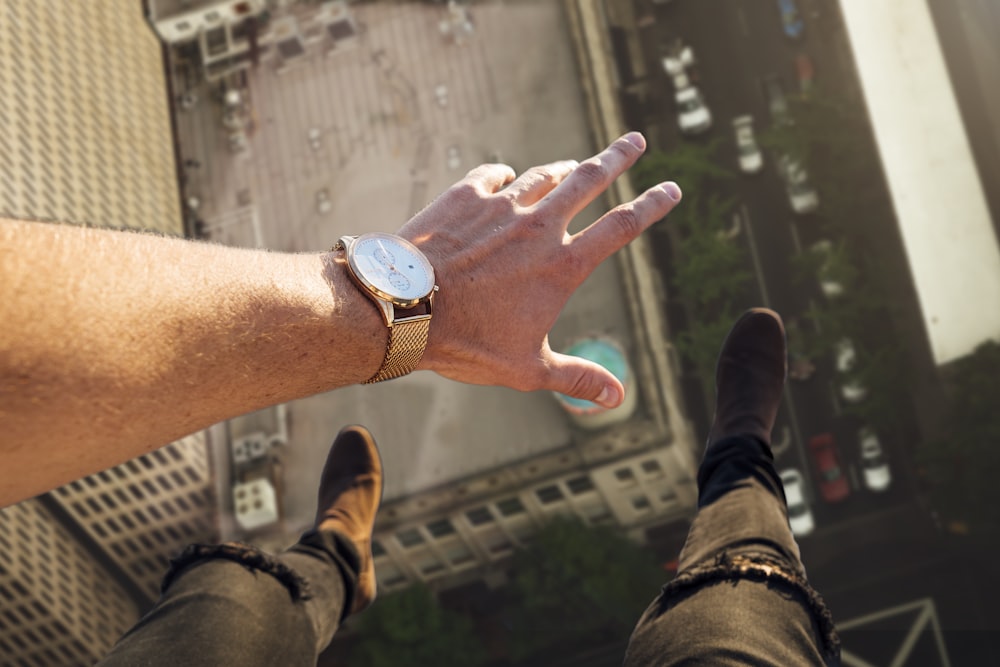 person wearing round gold-colored watch