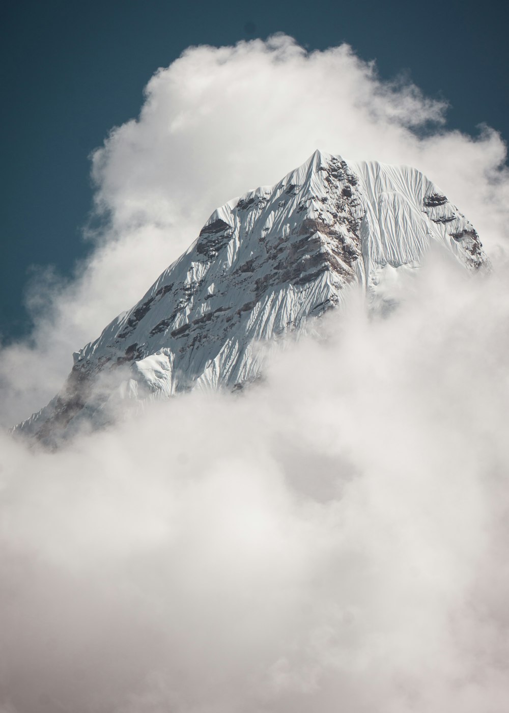 Fotografía de ángulo bajo de la cumbre de la montaña bajo el cielo blanco y azul durante el día
