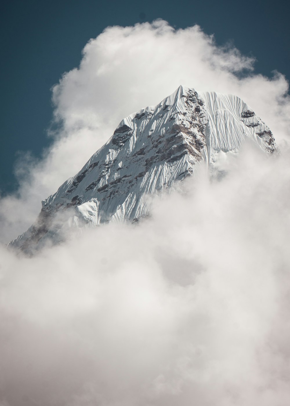 low-angle photography of summit of mountain under white and blue sky during daytime