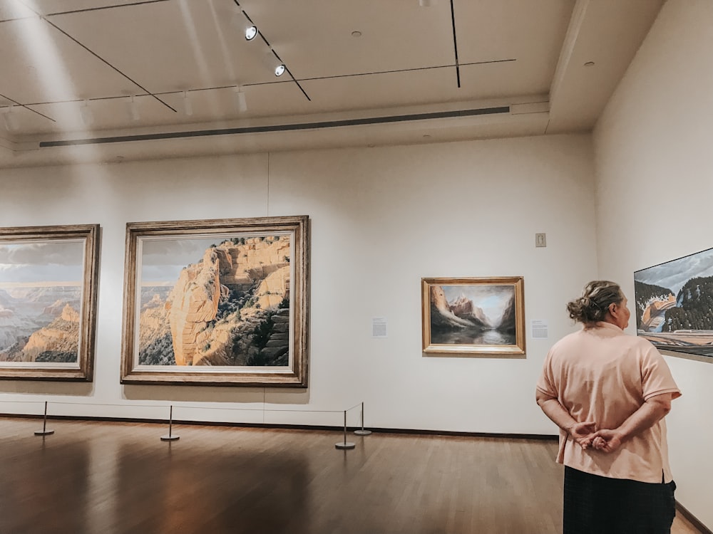 woman standing and staring on different paintings inside building