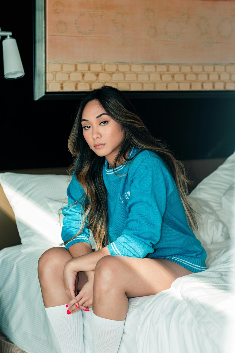 woman wearing blue sweater sitting on bed