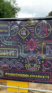 A vibrant banner with neon-style illustrations and text, featuring images of noodles, ice cream, a champagne glass, and various abstract shapes. There is also the hashtag #NIGHTNOODLEMARKETS displayed prominently.