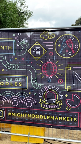 A vibrant banner with neon-style illustrations and text, featuring images of noodles, ice cream, a champagne glass, and various abstract shapes. There is also the hashtag #NIGHTNOODLEMARKETS displayed prominently.