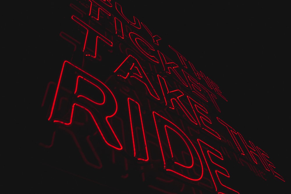 a red neon sign is lit up in the dark