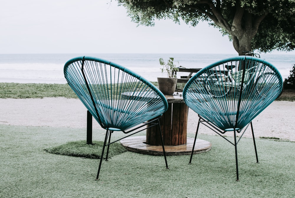 two blue chairs beside round table near ocean