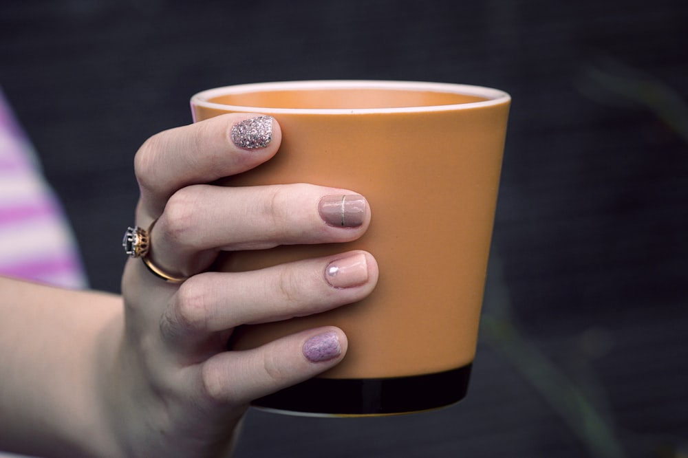 person holding orange cup