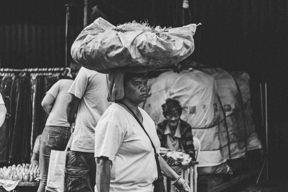 Una foto in bianco e nero di un uomo che porta qualcosa sulla testa