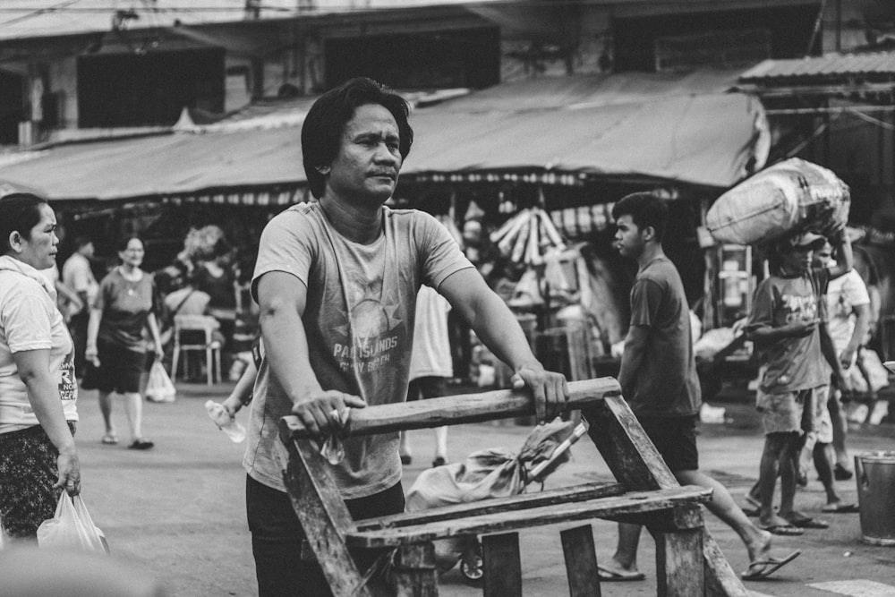 greyscale photography of man pushing cart