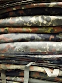 A wide shot of various arms laid out on a camouflage fabric.