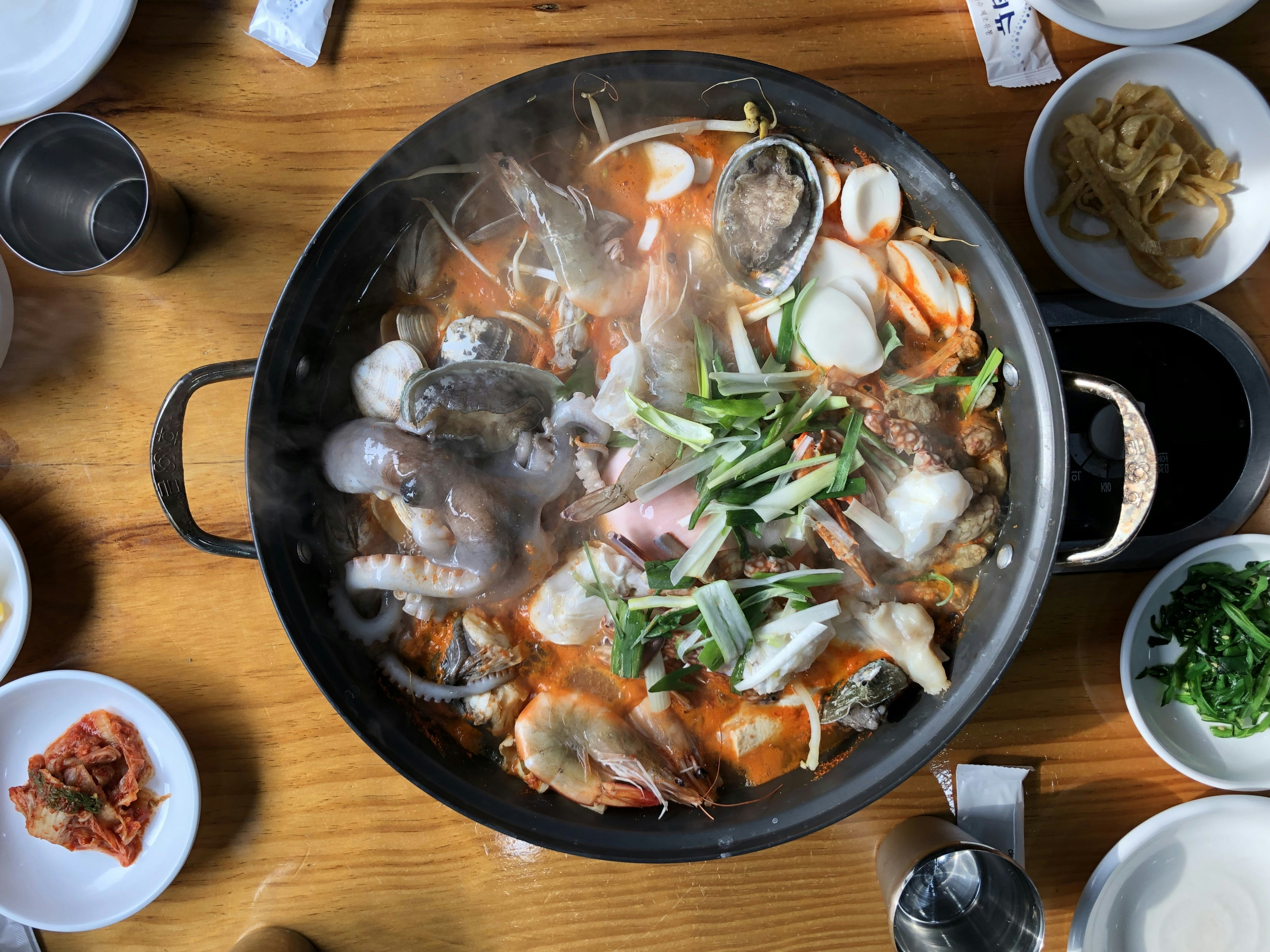 Spicy Korean seafood stew in large pot with shrimp, clams, and vegetables