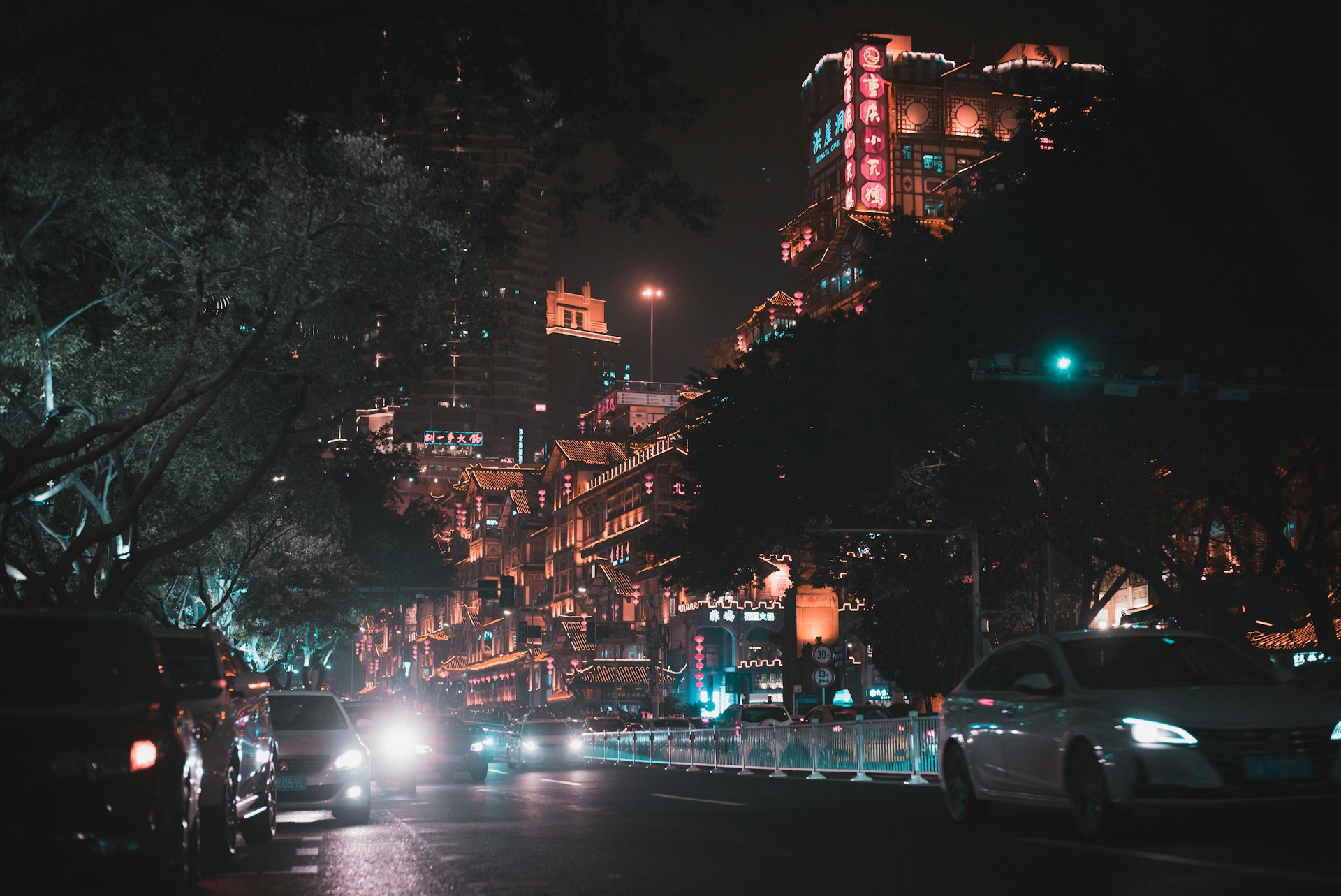 vehicles on road near trees and buildings at night
