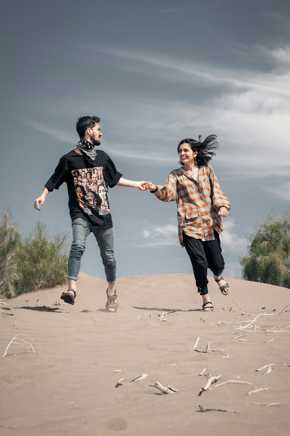 Hombre sosteniendo la mano de una mujer sonriente que camina sobre la arena durante el día