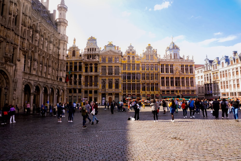 people walking near Grand Palace, Brussels Town Hall under white and blue sky during daytime