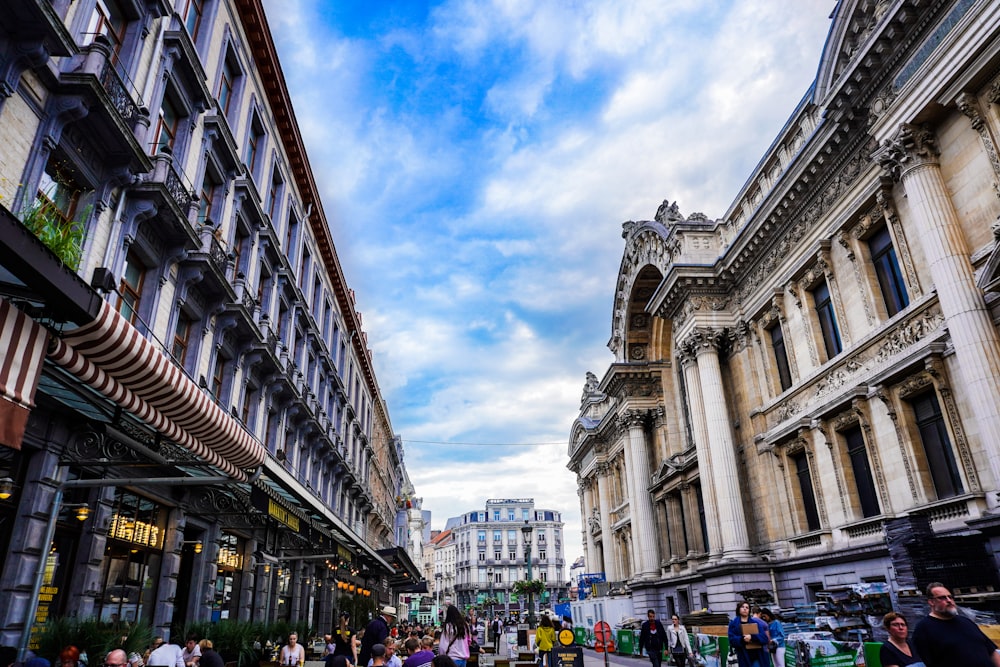 pessoas caminhando perto de edifícios históricos marrons sob o céu branco e azul durante o dia