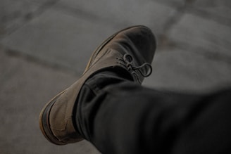 A close-up of a polished leather shoe paired with a crisp dress shirt and tie.