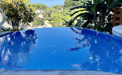 A tranquil infinity pool reflecting the pastel colors of dawn, surrounded by lush greenery.