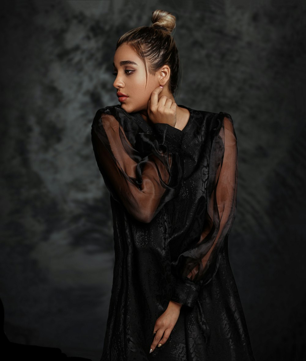 selective focus photography of standing woman wearing black long-sleeved dress