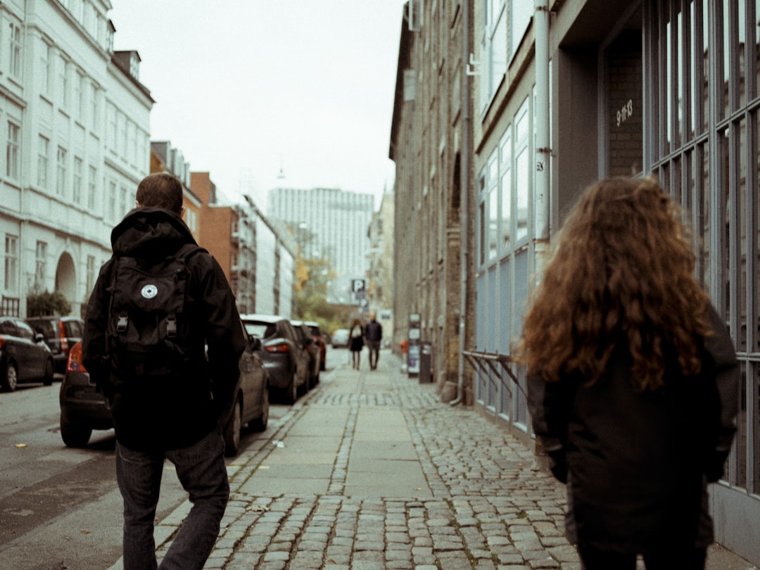 few people walking on pathway near different vehicles on road during daytime