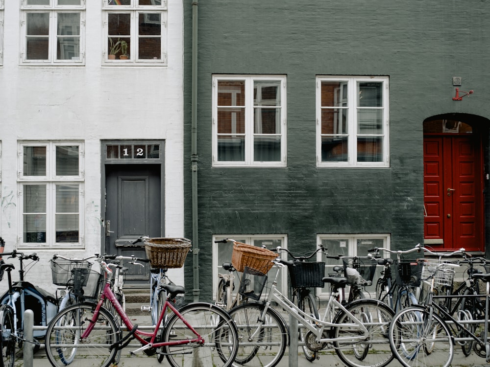 assorted-colored bikes parking near white and gray building during daytime