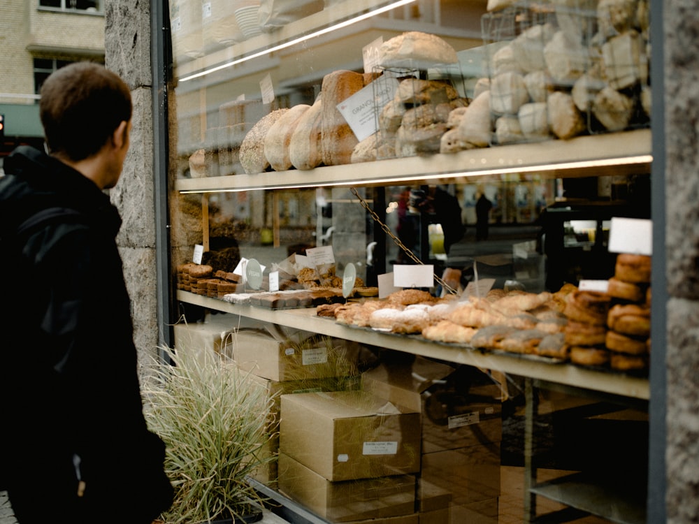 man wearing black jacket standing near glass window