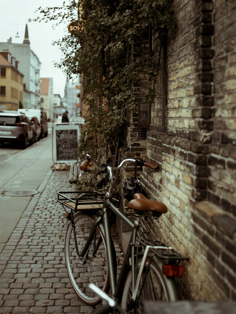 gray and brown commuter bike park beside wall near road during daytime