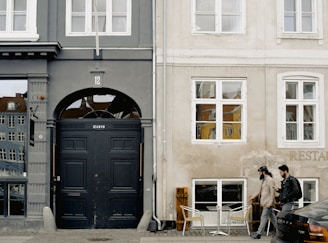 two men passing parked vehicle and closed building door