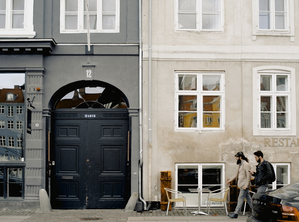 two men passing parked vehicle and closed building door