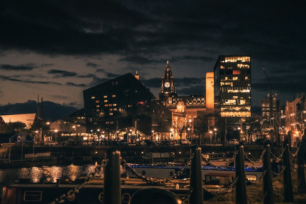 boats on body of water viewing city with high-rise buildings during night time