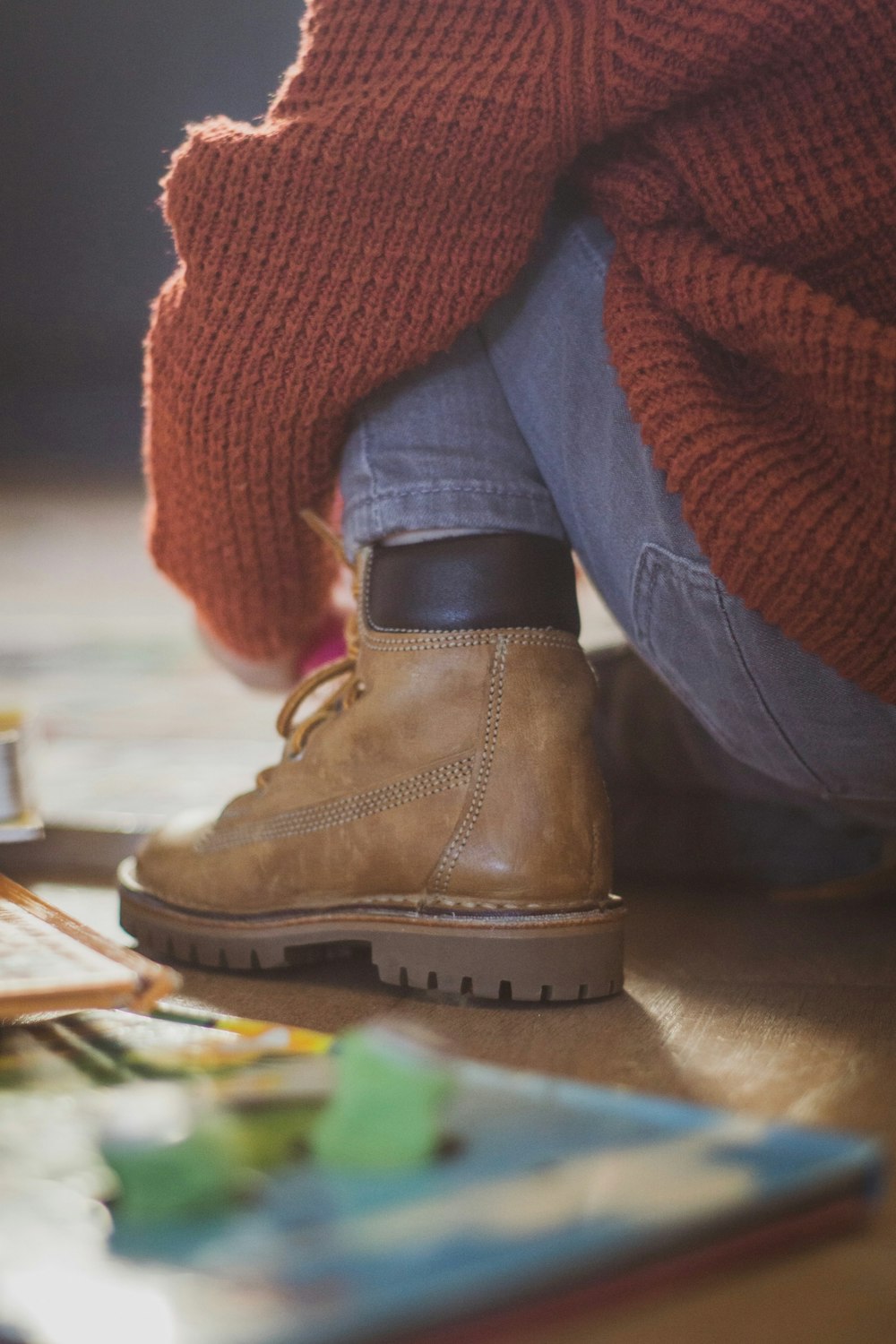 person wearing orange knit sweater, blue denim jeans, and brown leather work boots