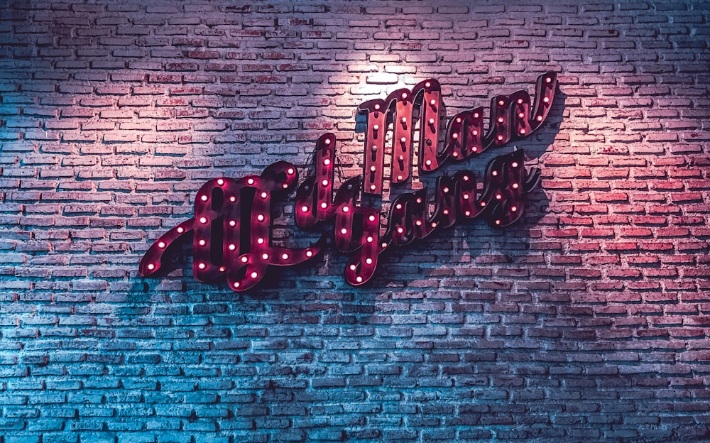 red LED signage on brick wall