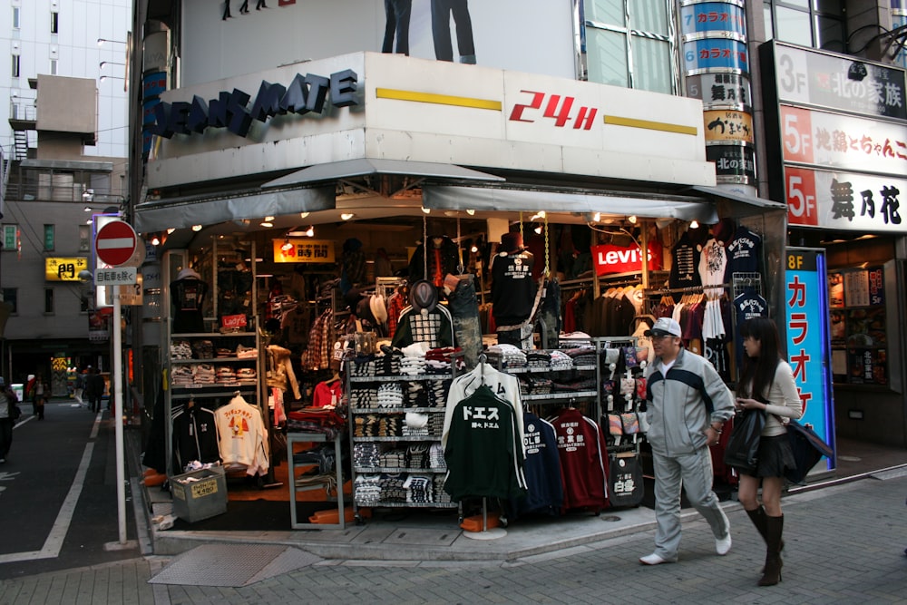 man and woman walking on street near 24H store during night time