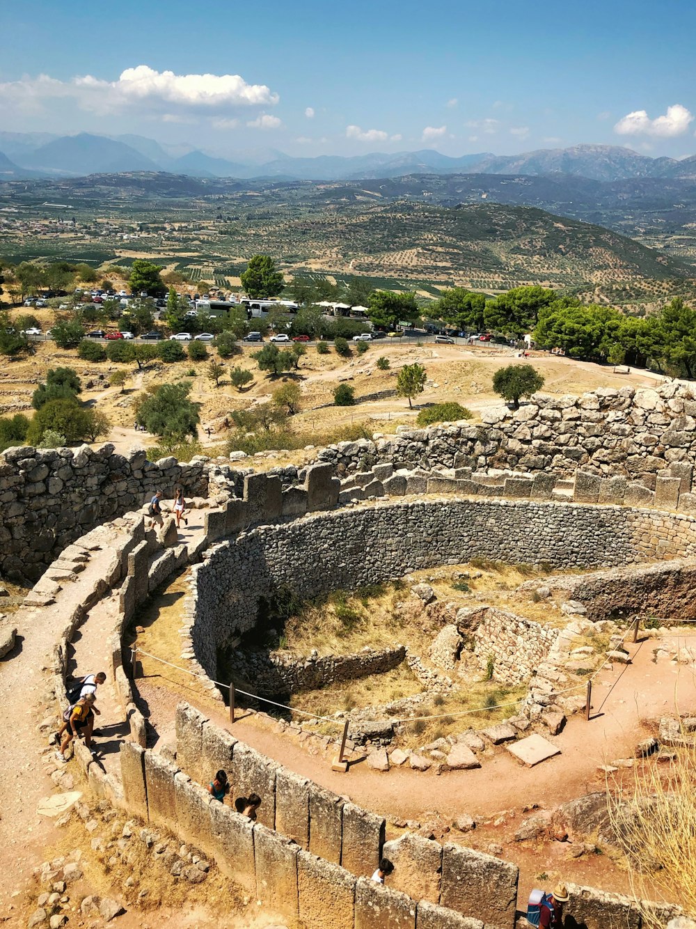 ruinas de hormigón gris cerca de árboles verdes bajo cielo azul y nubes blancas