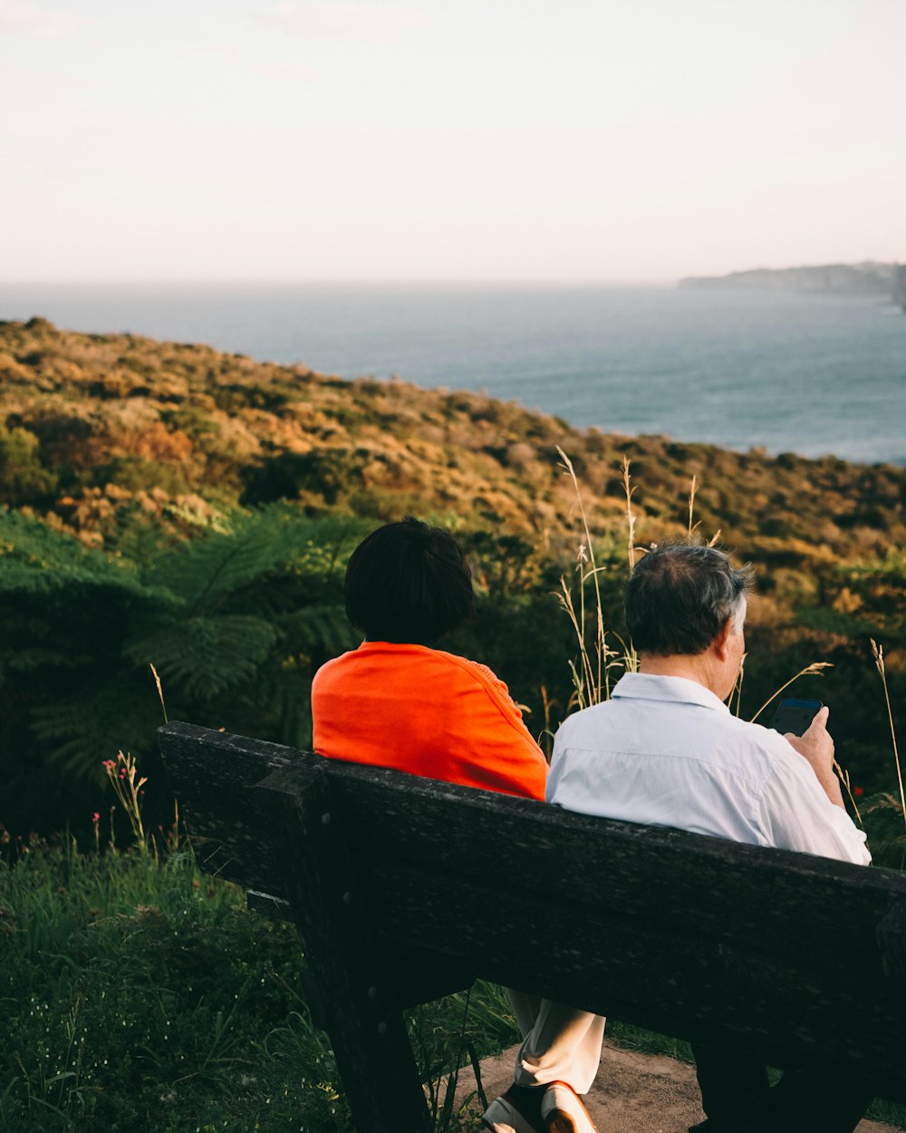 two people sitting on bench near body of water