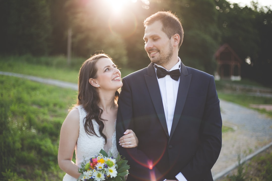 man wearing black tuxedo standing with woman holding bouquet flower