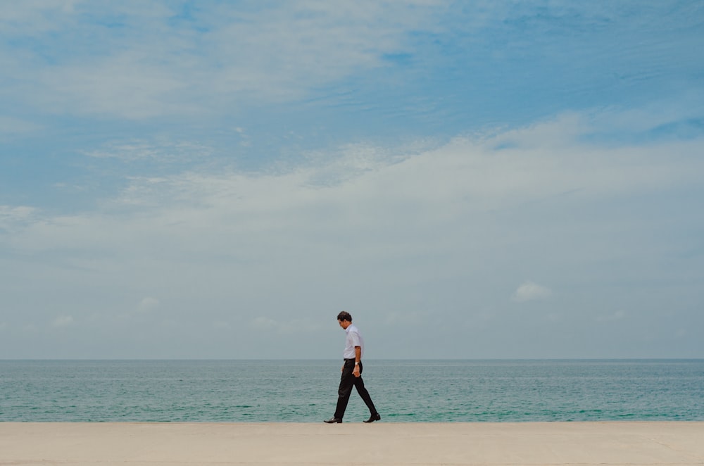 homme marchant sur le rivage près d’un plan d’eau